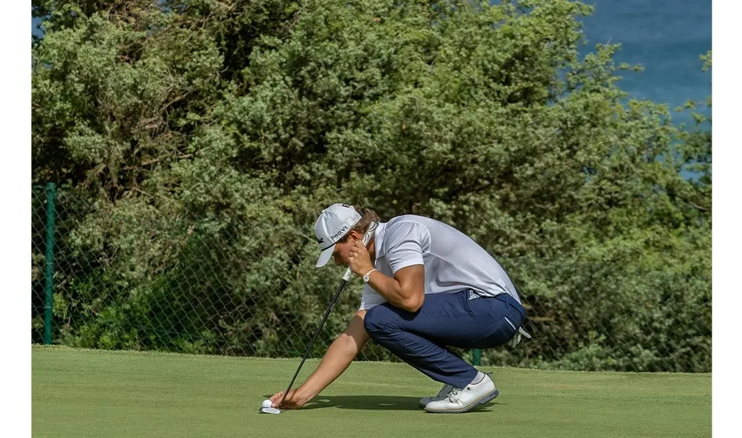 Golfista coloca su bola en el green del hoyo 6 del campo Mar y Pinos, con el mar de fondo en Novo Sancti Petri