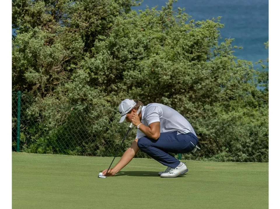 Golfista coloca su bola en el green del hoyo 6 del campo Mar y Pinos, con el mar de fondo en Novo Sancti Petri